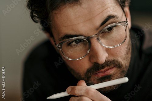 Serious male professional with digitized pen working at home office photo