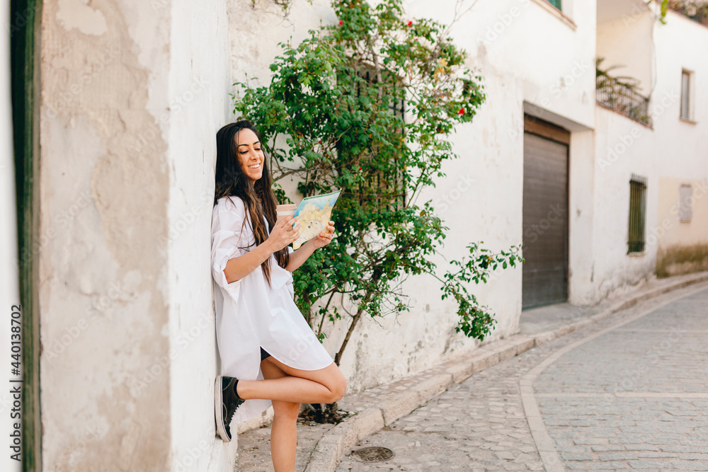 Smiling woman checking map while standing on footpath Smiling woman checking map while standing on footpath