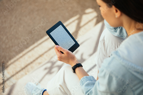 Woman reading an e-book while sitting on steps photo