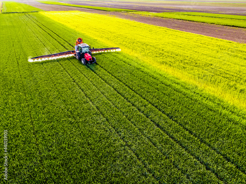 Crop sprayer sprinkling pesticide on wheat crop photo