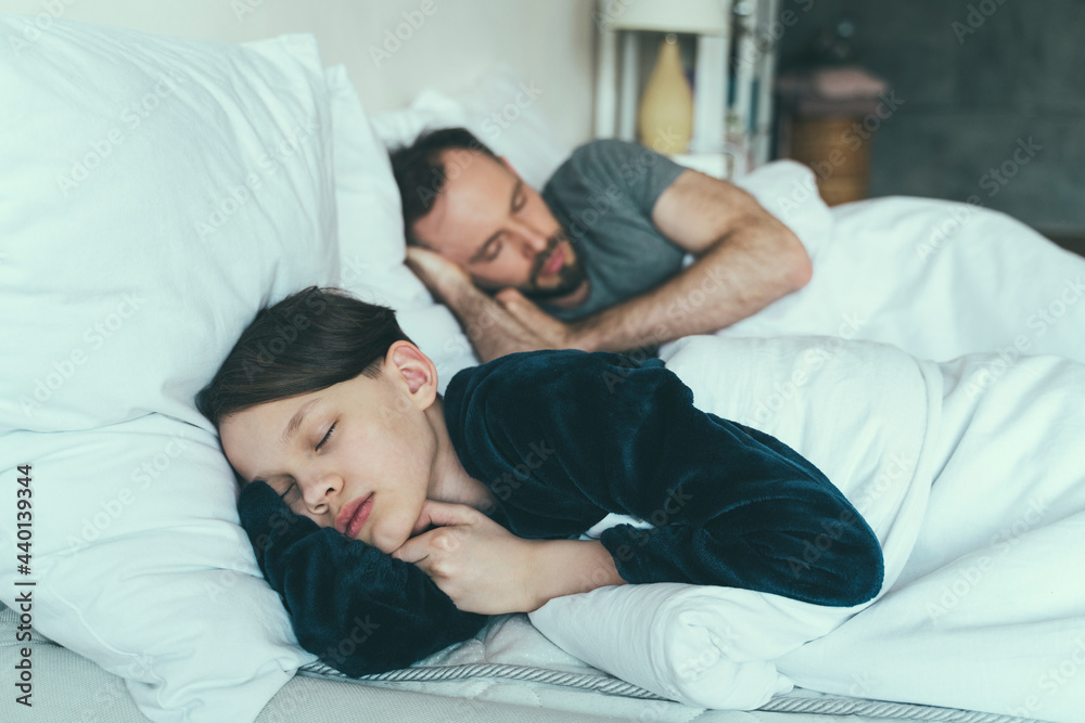 Son sleeping with father on bed at home Son sleeping with father on bed at home