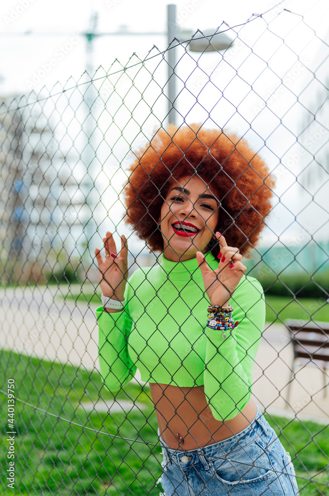 Redheaded woman on leaning fence in public park Redheaded woman on leaning fence in public park