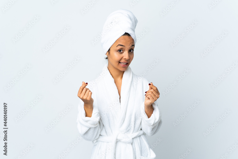 Young woman in bathrobe over isolated white background making money gesture Young woman in bathrobe over isolated white background making money gesture