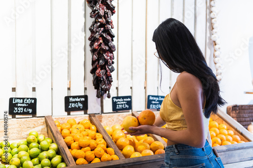 Young woman with long hair buying oranges at grocery store photo