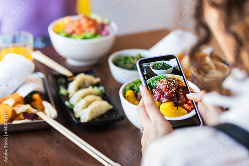 Woman photographing food through mobile phone in restaurant photo