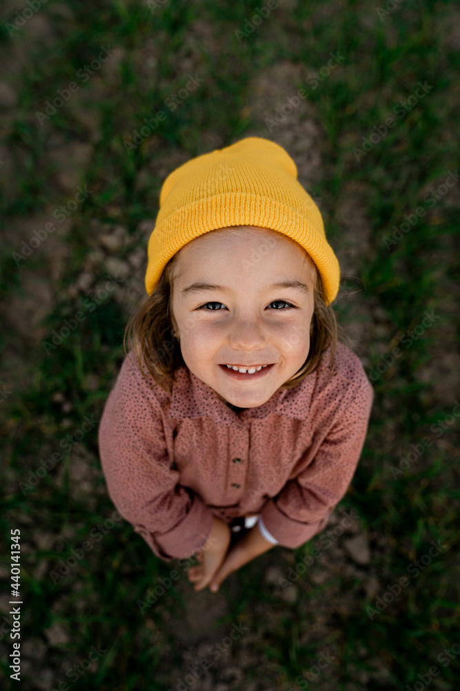 Smiling cute girl wearing knit hat standing on agricultural field Smiling cute girl wearing knit hat standing on agricultural field