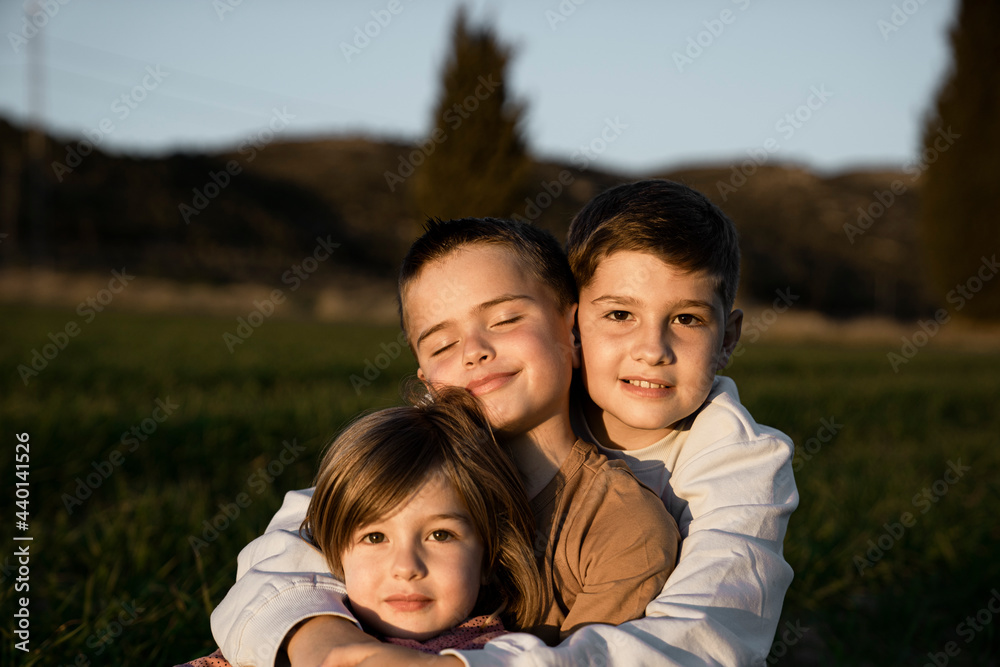 Brother and sister sitting with arms around at agricultural field Brother and sister sitting with arms around at agricultural field