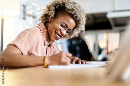 Businesswoman with eyeglasses writing while working at home office