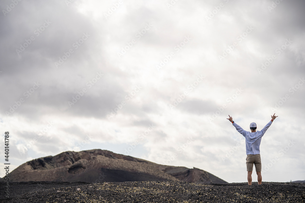 Male tourist with arms outstretched standing at volcanic landscape Male tourist with arms outstretched standing at volcanic landscape
