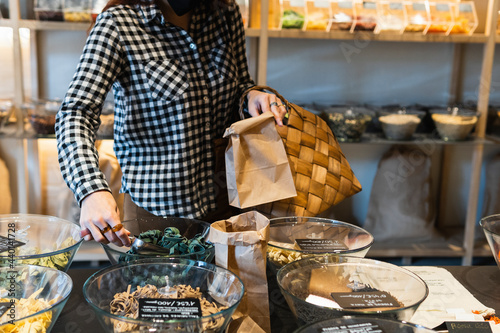 Woman putting spice in paper bag at store photo