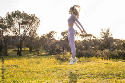 Female athlete jumping while exercising at grass area photo