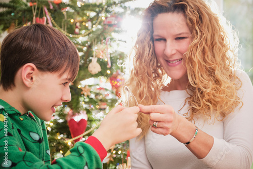 Happy mother and son holding wishbone with Christmas tree in background
