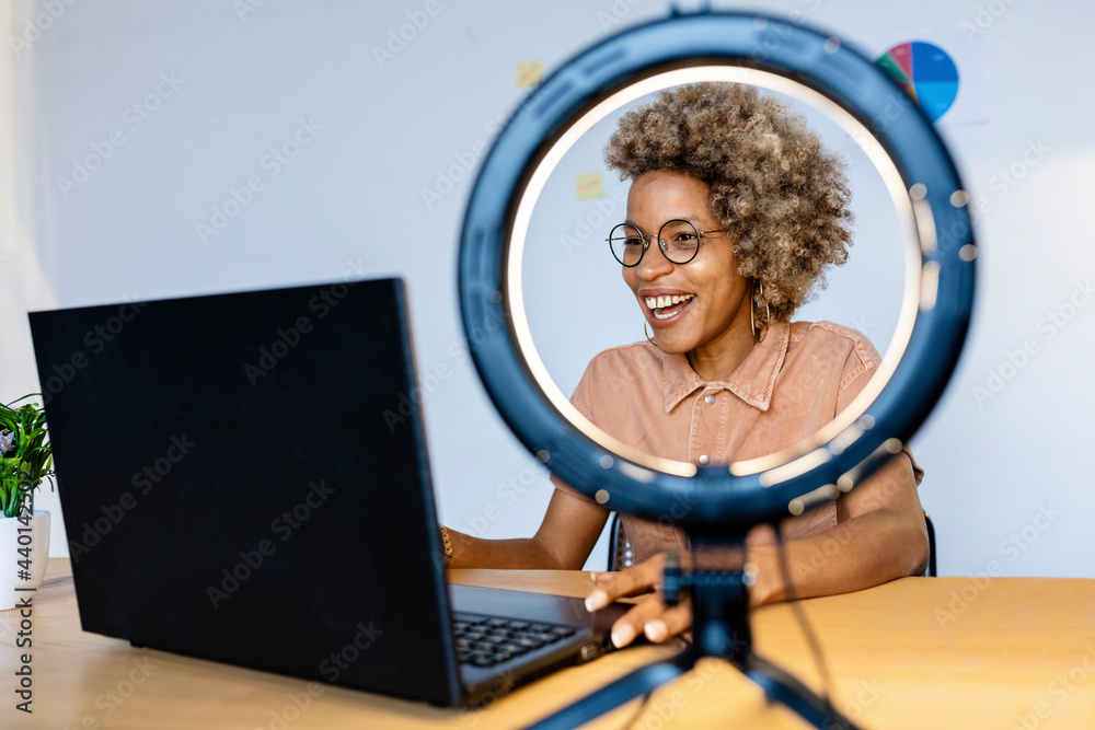 © Rafael Fernandez Torres/Westend61 - Female influencer sitting with ring light using laptop at home office