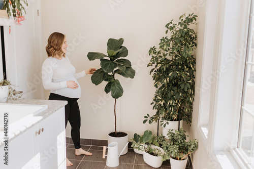 Smiling woman looking at potted plant in living room
