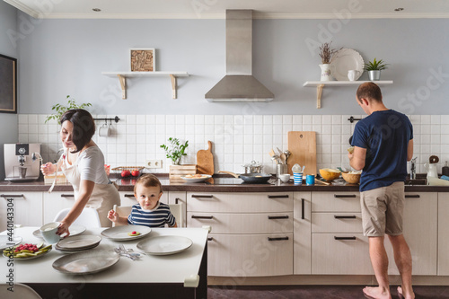 Father and mother with cute son preparing food in kitchen photo