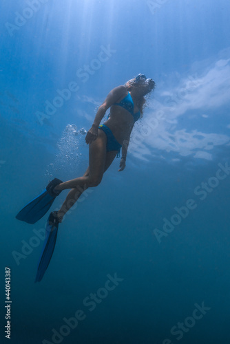 Underwater view of young woman diving in Java Sea
