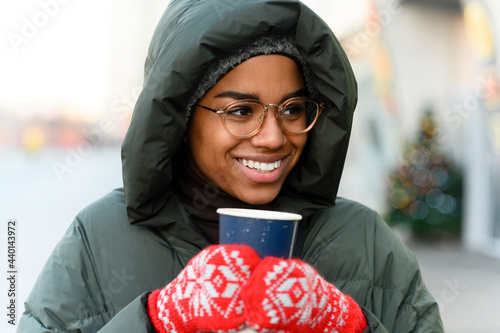 Smiling woman with reusable cup wearing gloves in winter photo