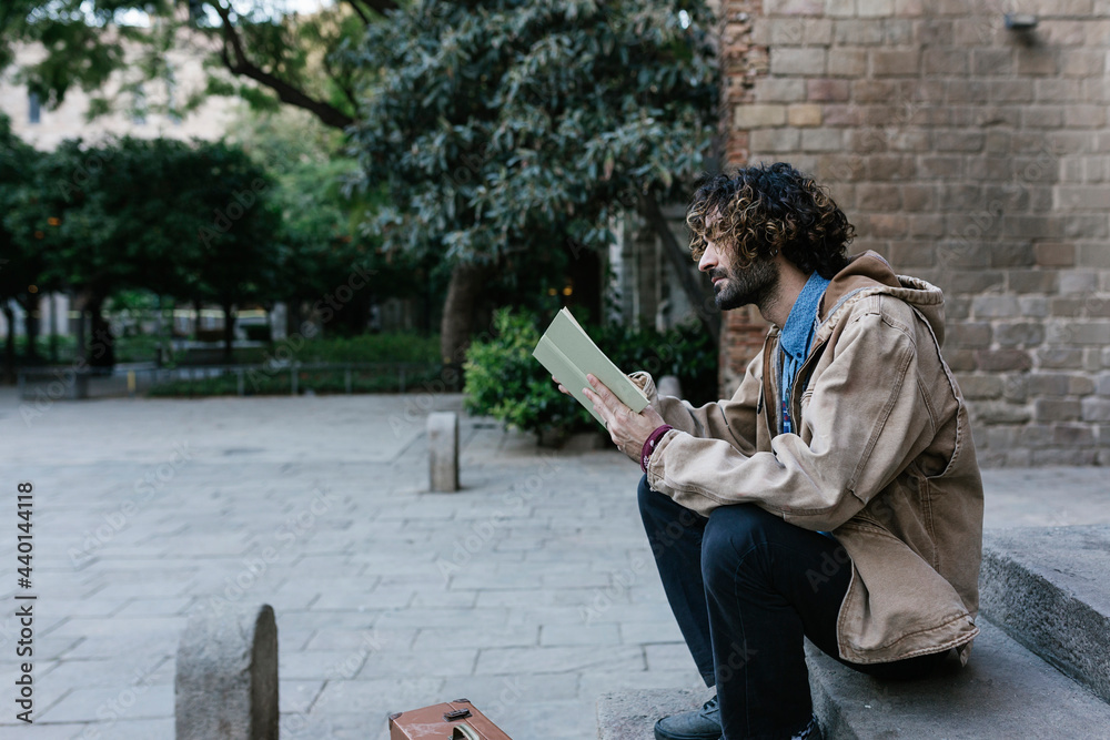 Young man reading book while sitting on steps Young man reading book while sitting on steps