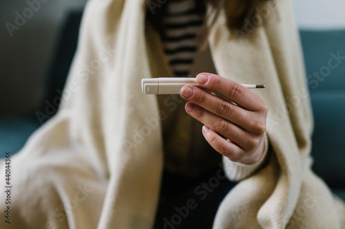 Woman holding thermometer at home photo
