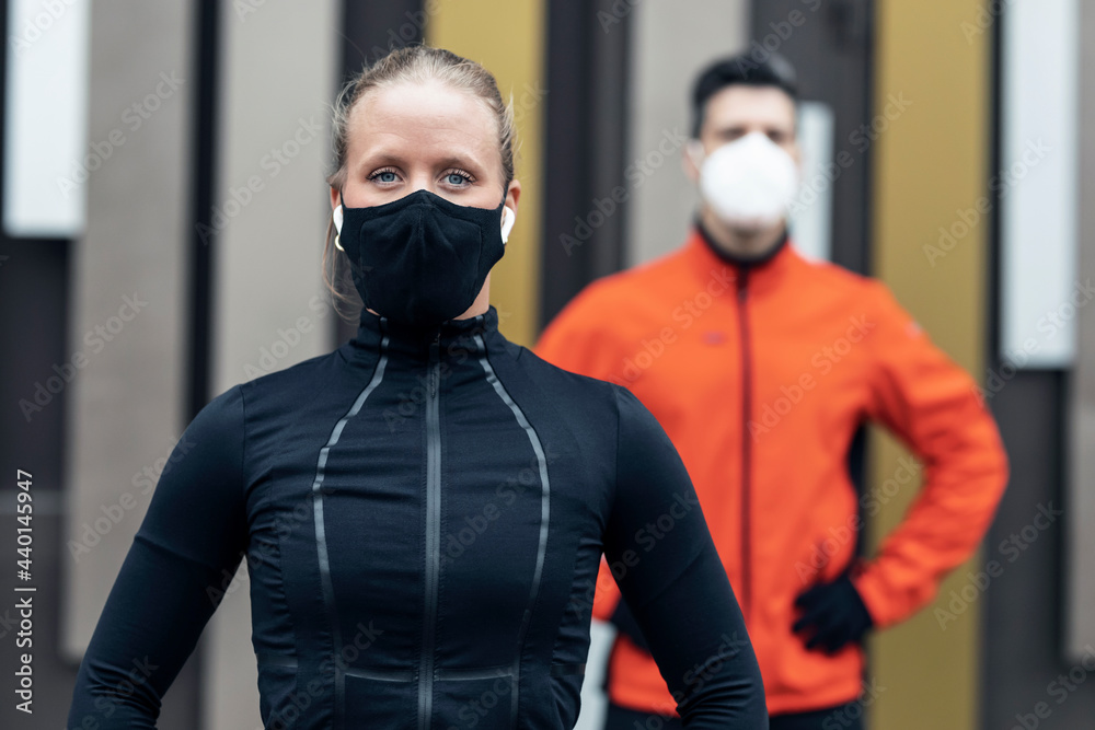 Male and female friends with protective face masks and sports clothing during pandemic Male and female friends with protective face masks and sports clothing during pandemic