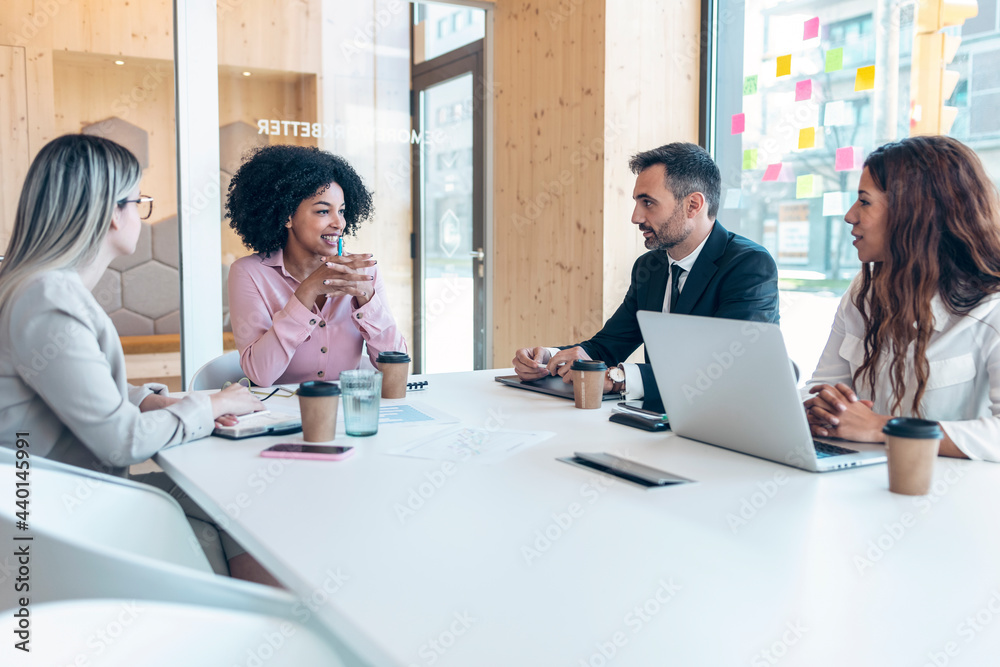 Multi-ethnic male and female professionals discussing during meeting in office Multi-ethnic male and female professionals discussing during meeting in office