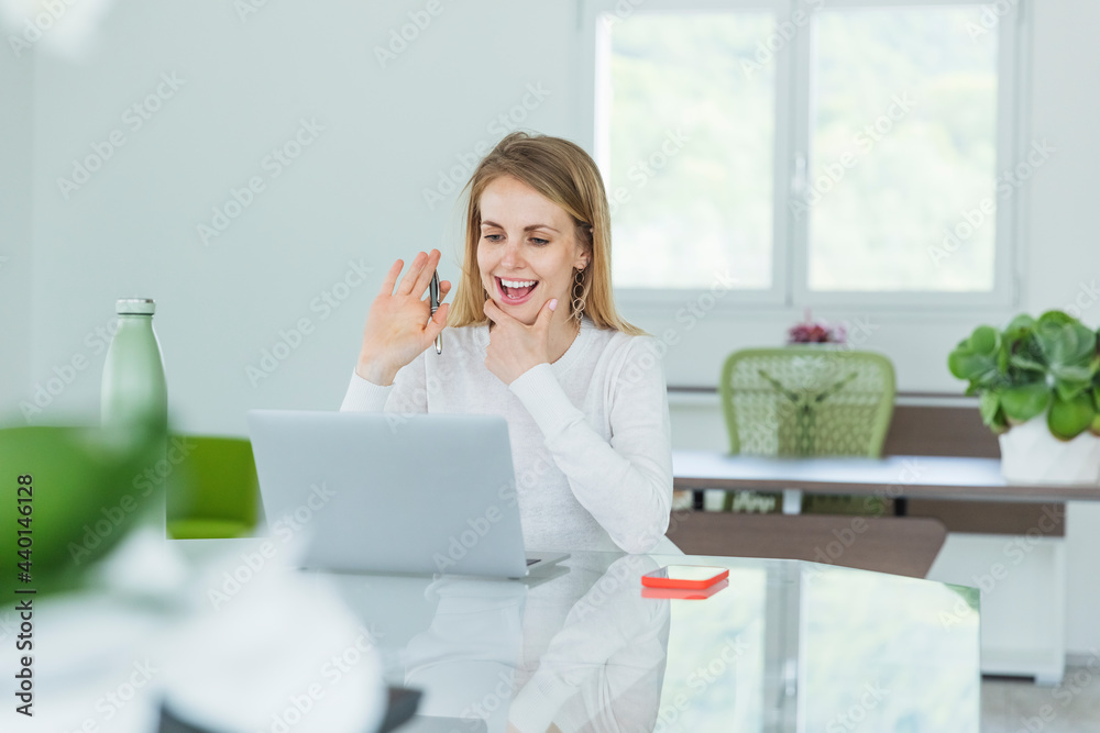 Smiling businesswoman waving during video conference on laptop at office Smiling businesswoman waving during video conference on laptop at office