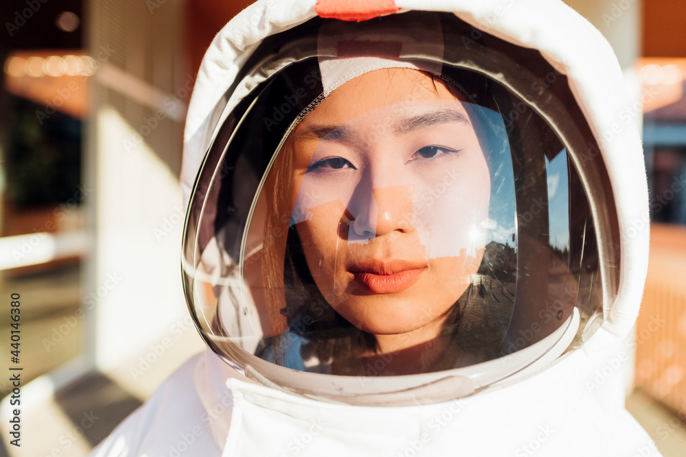 Serious female astronaut in space suit during sunny day Serious female astronaut in space suit during sunny day