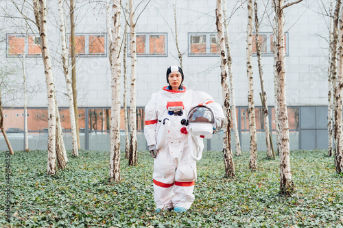 Female astronaut holding space helmet while standing in garden photo