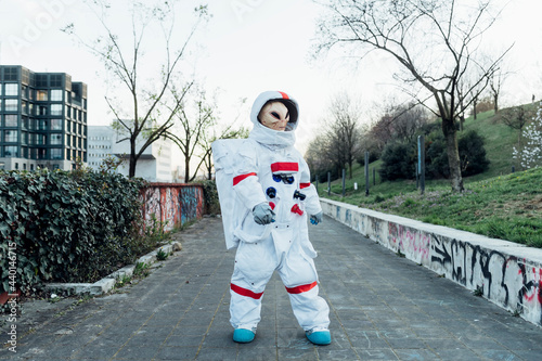 Female astronaut with alien mask standing on footpath photo