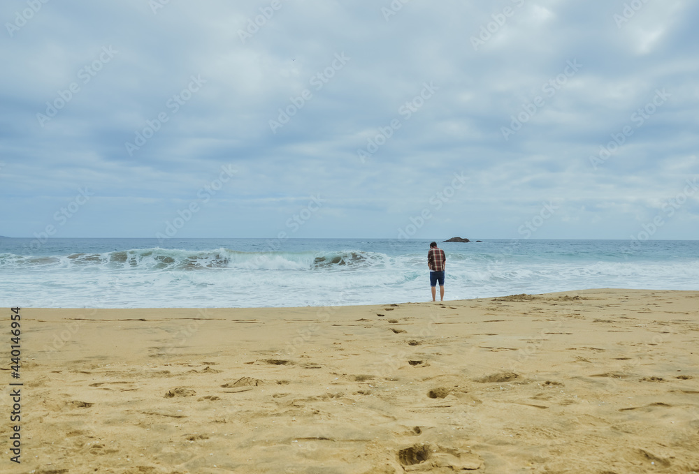 Man walks towards the sea leaving footprint in the sand