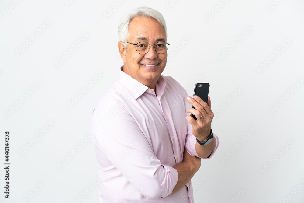 Middle age Brazilian man isolated on white background holding a mobile phone and with arms crossed Middle age Brazilian man isolated on white background holding a mobile phone and with arms crossed
