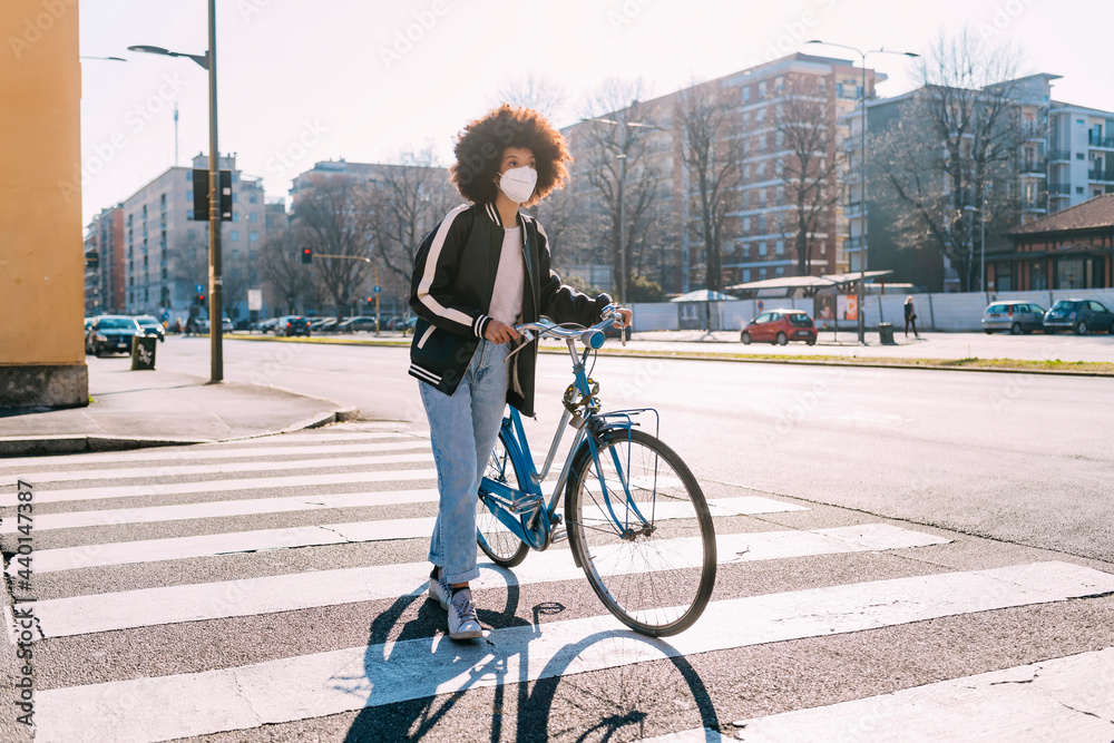 Woman wearing protective face mask walking with bicycle on road in city Woman wearing protective face mask walking with bicycle on road in city