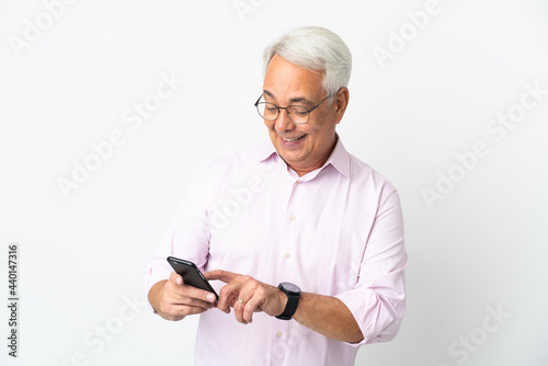 Middle age Brazilian man isolated on white background sending a message or email with the mobile