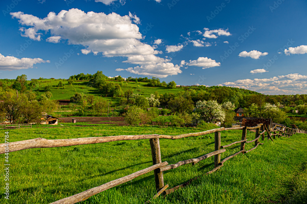 wooden fence on a meadow in a hilly area on a sunny day, rural landscape.