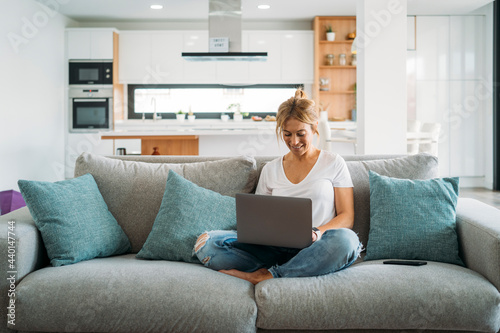 Female professional using laptop while sitting on sofa at home photo