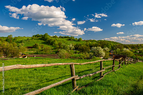 Obraz na płótnie wooden fence on a meadow in a hilly area on a sunny day, rural landscape. w salonie