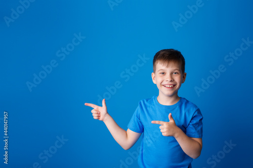  boy on a blue background points his finger to the side and free space