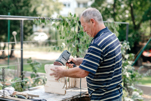 Active senior man with woodworking tool doing carpentry in backyard photo