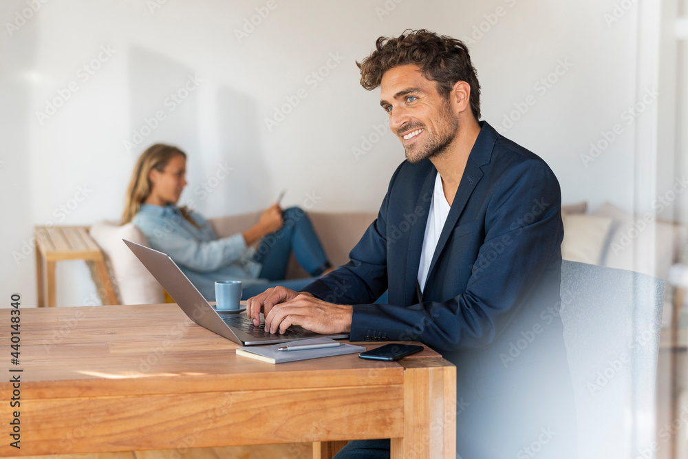 Contemplating man with laptop on table while girlfriend sitting at home office