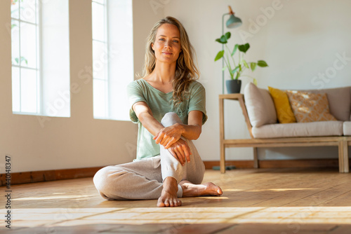 Confident woman in loungewear sitting on floor at home photo