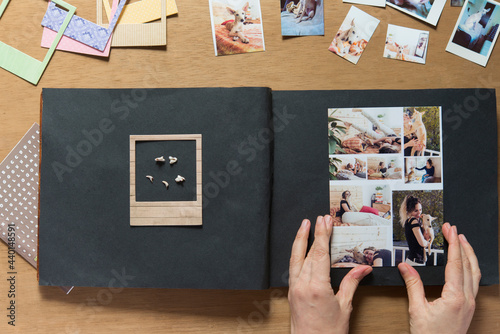 Woman sticking collage photo of dog in scrapbook photo