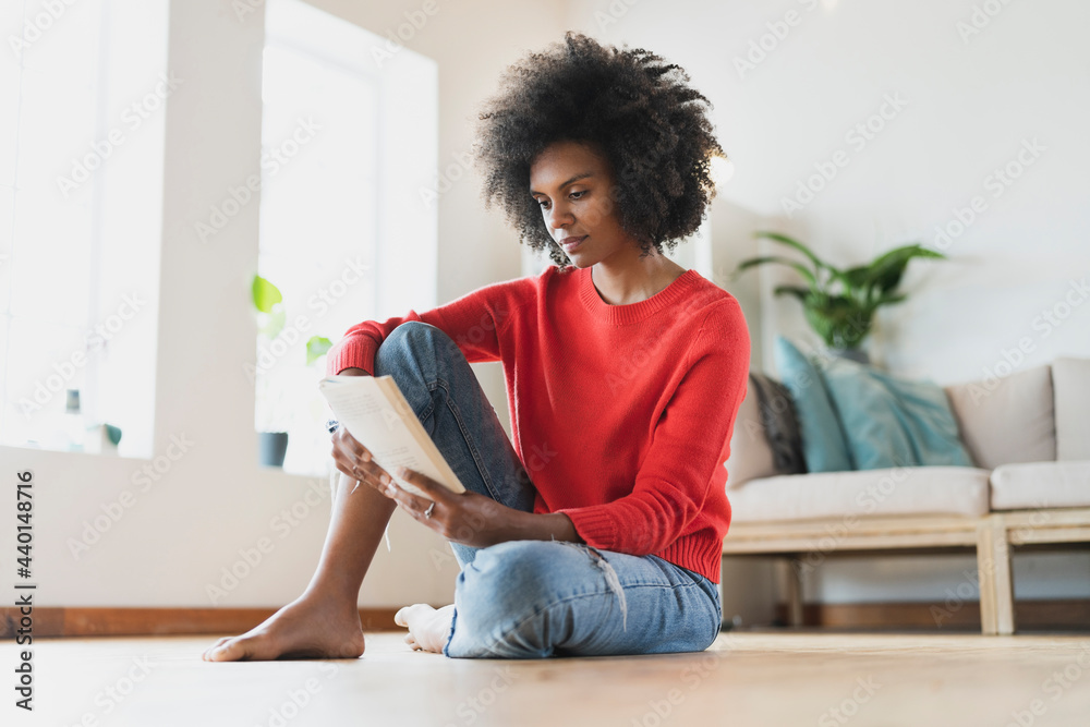 Young woman reading book while sitting in living room Young woman reading book while sitting in living room