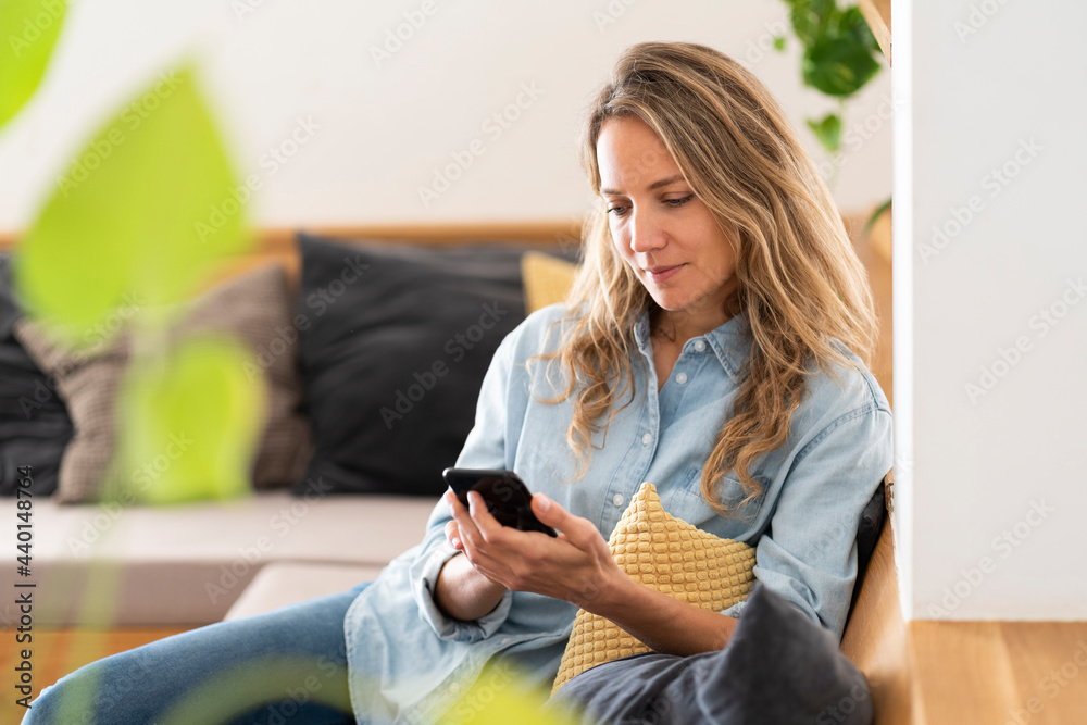 © steve brookland/Westend61 - Mid adult woman surfing net while sitting on couch © steve brookland/Westend61 - Mid adult woman surfing net while sitting on couch