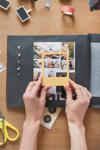 Woman holding frame over photo on scrapbook