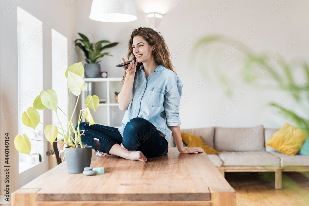 Smiling woman with crossed legs talking on mobile phone at home Smiling woman with crossed legs talking on mobile phone at home