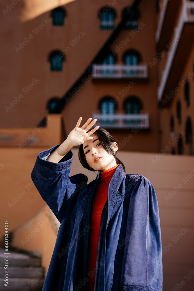 Young woman shielding eyes while standing in front of building during sunny day Young woman shielding eyes while standing in front of building during sunny day