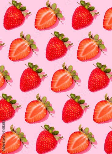 Pattern of rows of fresh halved strawberries lying against pink background photo