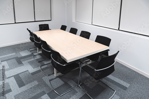 Black office chairs arranged around conference table in board room at work place