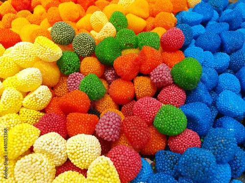 Bright and juicy gummy candies.  The chocolates are poured in a large pile of different colors and sizes.