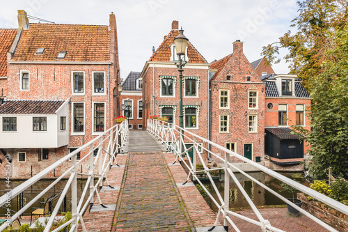 Netherlands, Groningen Province, Appingedam, Footbridge over Damsterdiep canal with brick townhouses in background